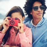 Fashionable hipster couple taking retro camera photo at beach